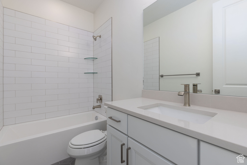 Full bathroom with tiled shower / bath, vanity with extensive cabinet space, and toilet