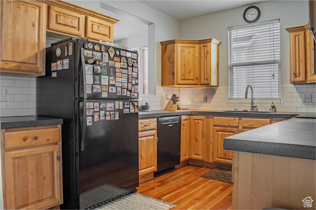 Kitchen featuring backsplash, sink, black appliances, and light hardwood / wood-style flooring