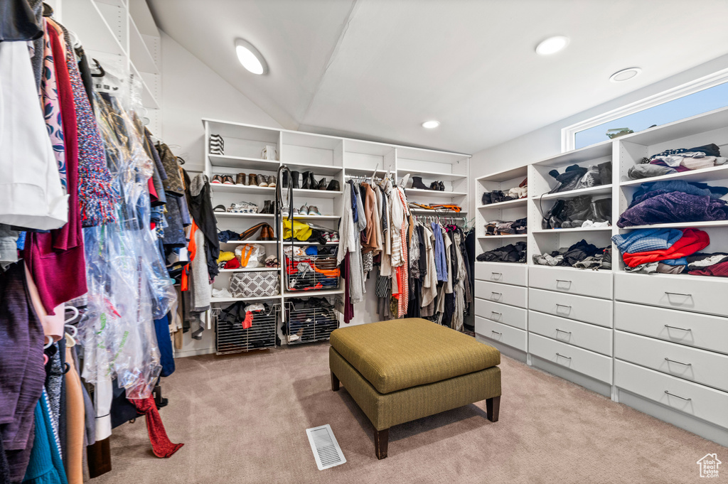 Walk in closet with vaulted ceiling and light colored carpet