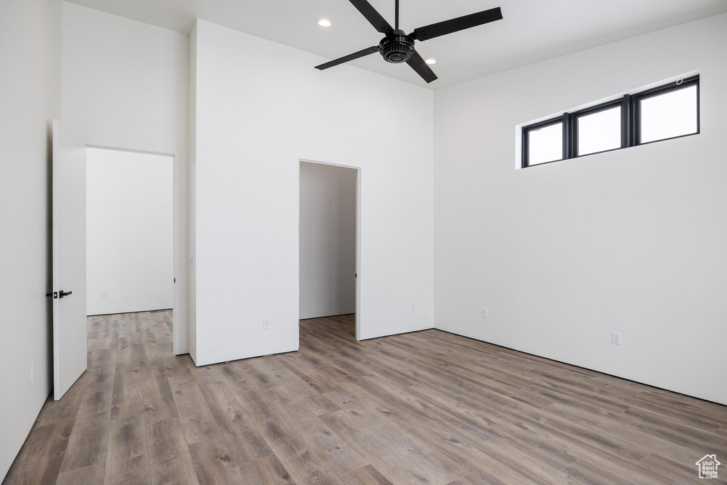 Unfurnished bedroom with ceiling fan, a closet, light hardwood / wood-style floors, and a walk in closet