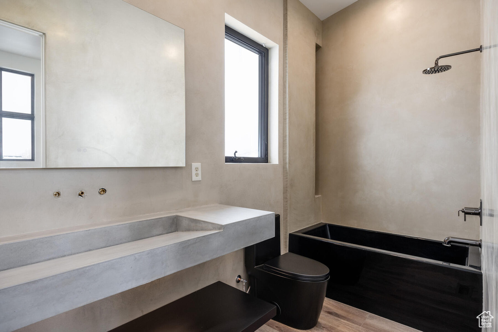 Full bathroom featuring a wealth of natural light, toilet, and hardwood / wood-style floors