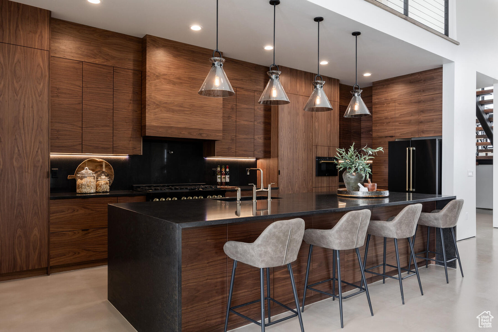 Kitchen with black appliances, an island with sink, a kitchen bar, and sink