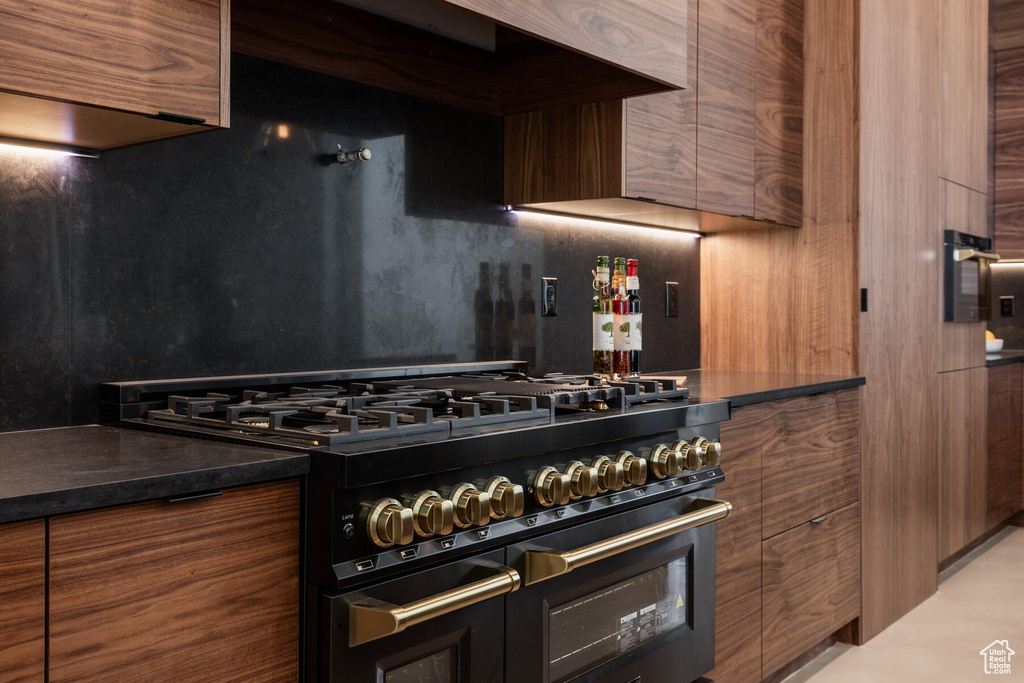 Kitchen with premium range hood, double oven range, and dark stone counters