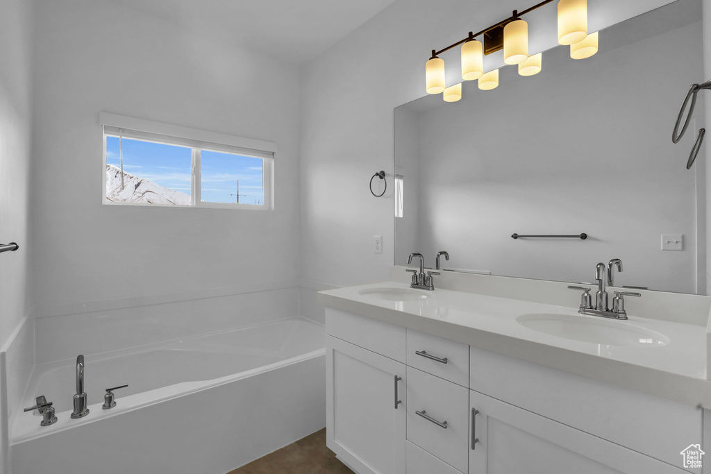 Bathroom featuring a tub, double sink, and large vanity