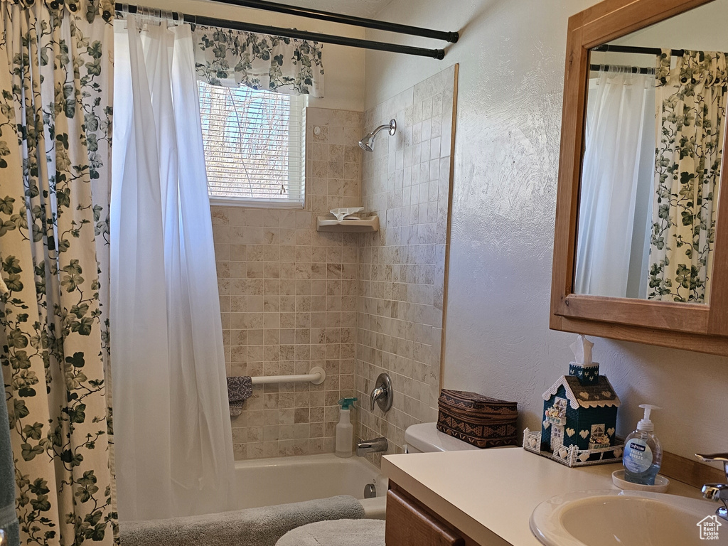 Full bathroom featuring a textured ceiling, shower / bath combo, toilet, tile flooring, and vanity