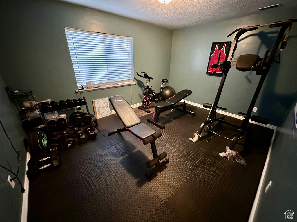 Exercise area featuring carpet floors and a textured ceiling