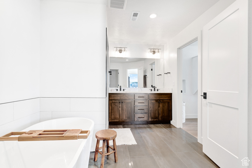 Bathroom featuring double sink vanity, hardwood / wood-style floors, and a tub