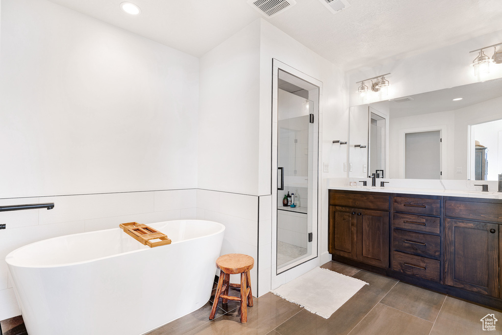 Bathroom with tile flooring, tile walls, double sink vanity, and plus walk in shower