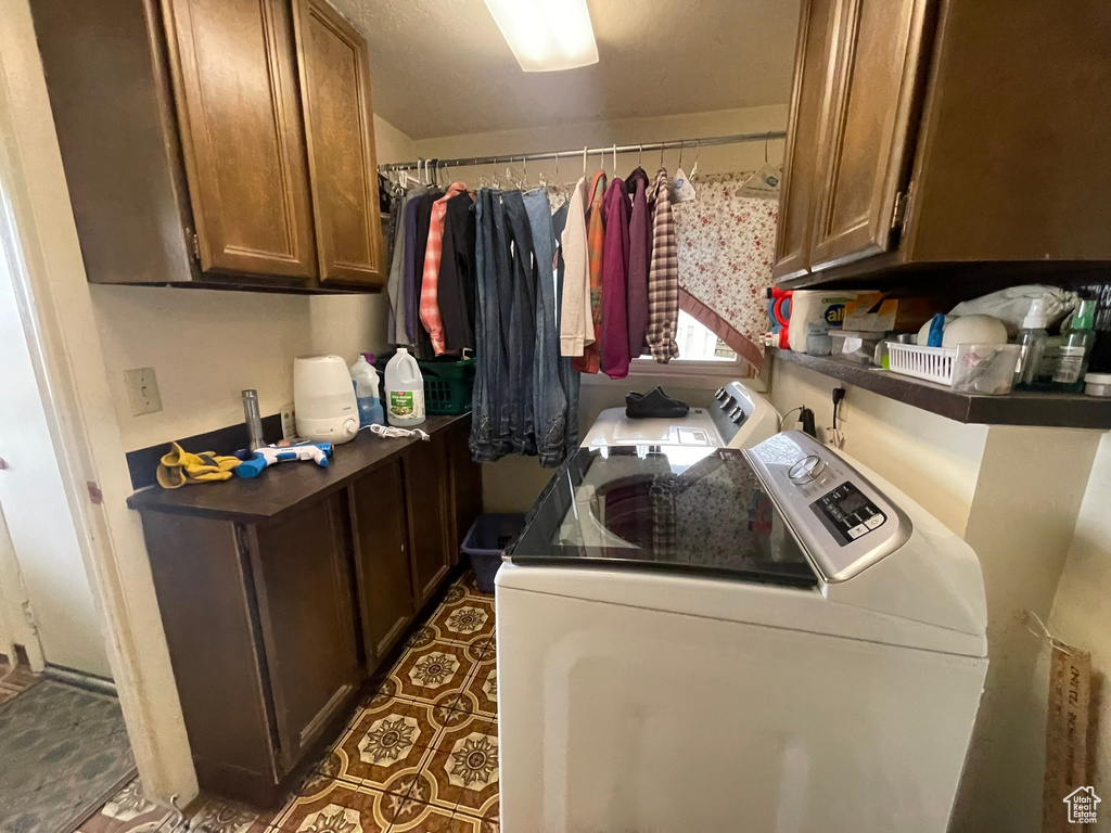 Laundry area featuring cabinets, separate washer and dryer, and dark tile floors