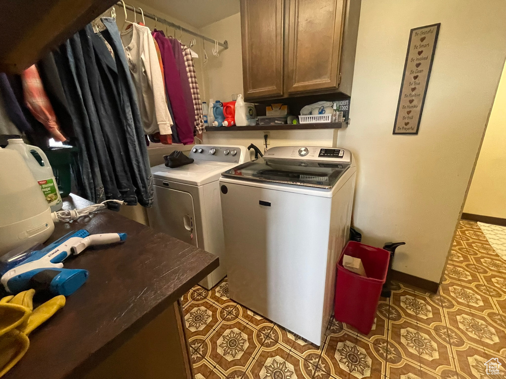 Laundry area featuring cabinets, dark tile flooring, and independent washer and dryer