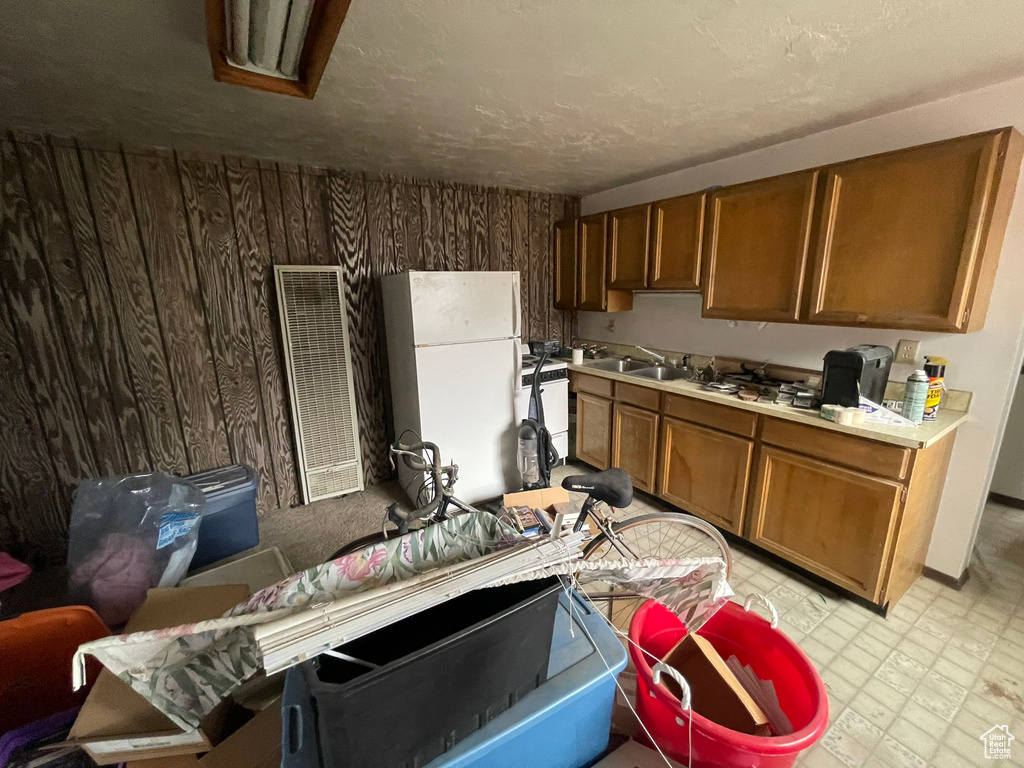 Kitchen with white refrigerator, wood walls, light tile floors, and dishwashing machine