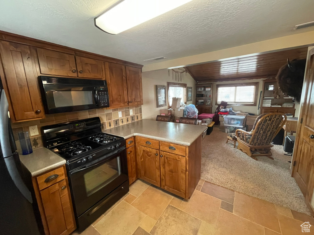 Kitchen with a textured ceiling, tasteful backsplash, kitchen peninsula, light tile floors, and black appliances