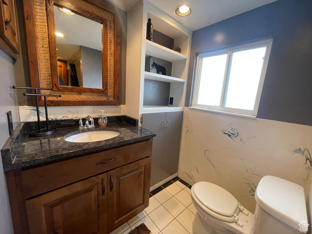 Bathroom featuring built in features, toilet, vanity with extensive cabinet space, and tile floors