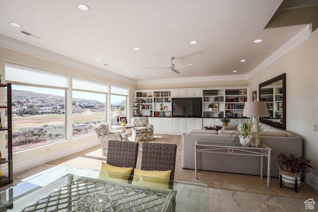 Living room featuring built in features, a mountain view, crown molding, and ceiling fan