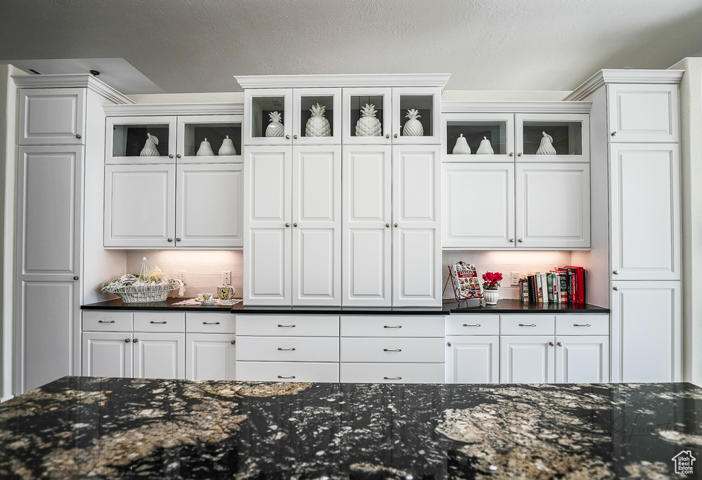 Interior space with dark stone counters and white cabinets