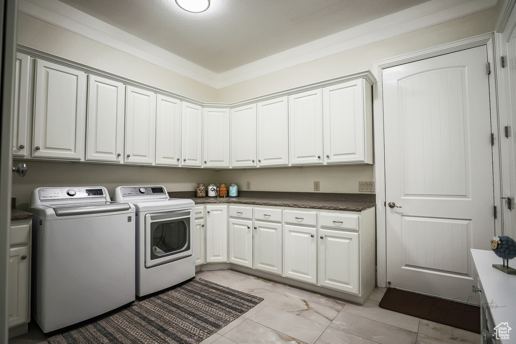 Washroom featuring light tile floors, ornamental molding, separate washer and dryer, and cabinets