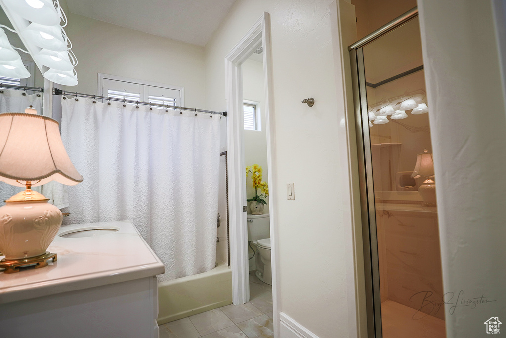 Full bathroom with vanity, toilet, shower / bathtub combination with curtain, and tile floors