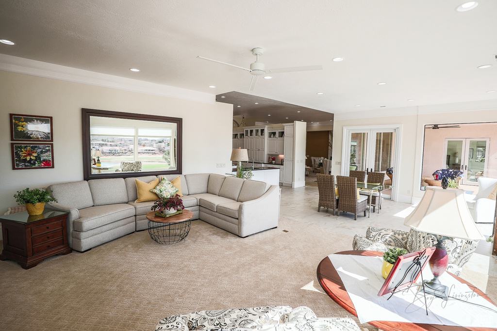 Carpeted living room with ornamental molding and ceiling fan