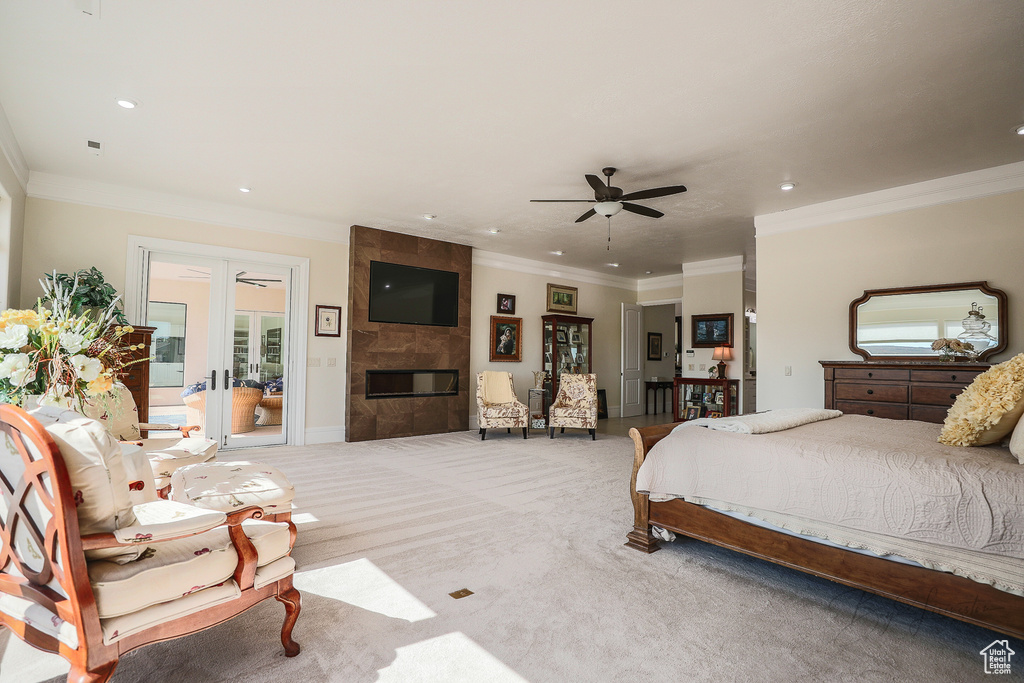 Carpeted bedroom featuring a tile fireplace, ornamental molding, and ceiling fan