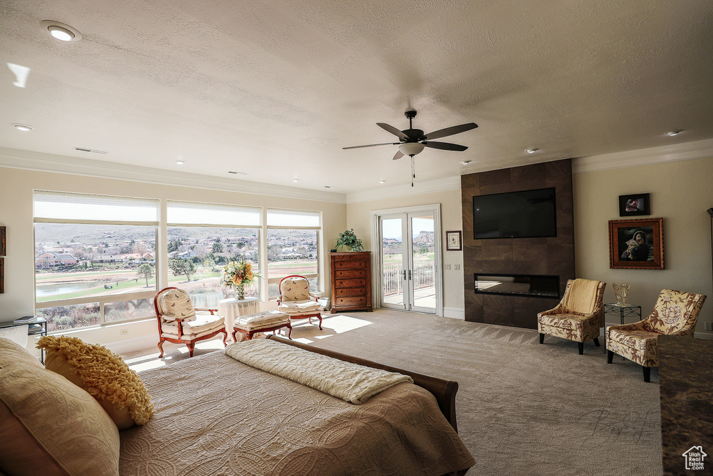 Bedroom featuring access to outside, french doors, a tiled fireplace, carpet floors, and ceiling fan