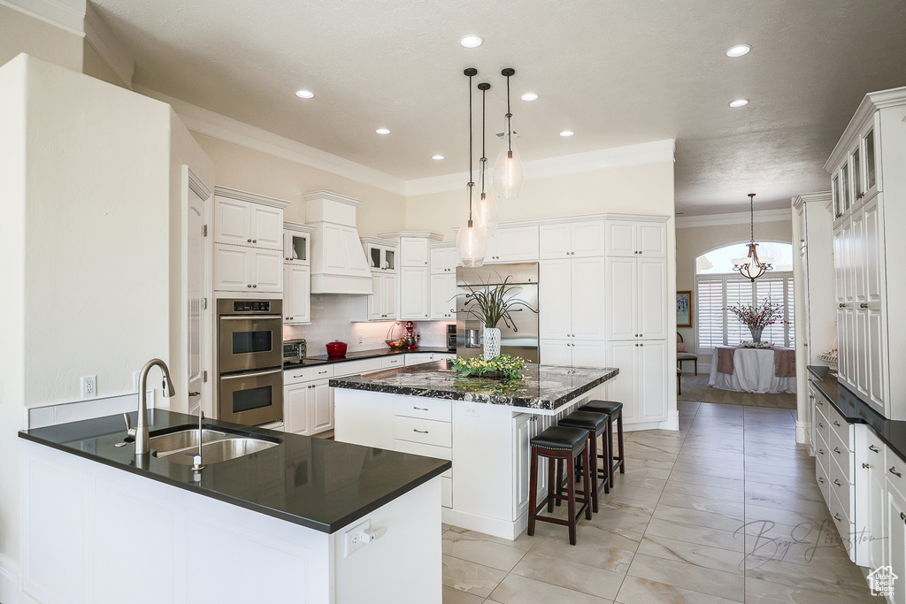Kitchen with a center island, a chandelier, hanging light fixtures, stainless steel appliances, and crown molding