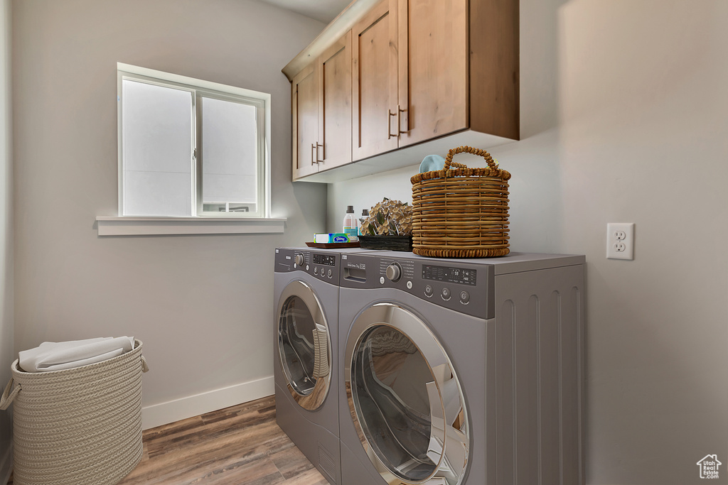 Laundry area with dark hardwood / wood-style flooring, cabinets, and washing machine and clothes dryer