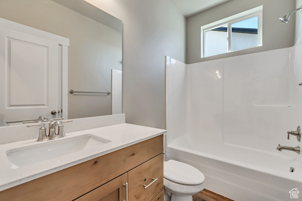 Full bathroom featuring shower / bath combination, toilet, large vanity, and hardwood / wood-style floors