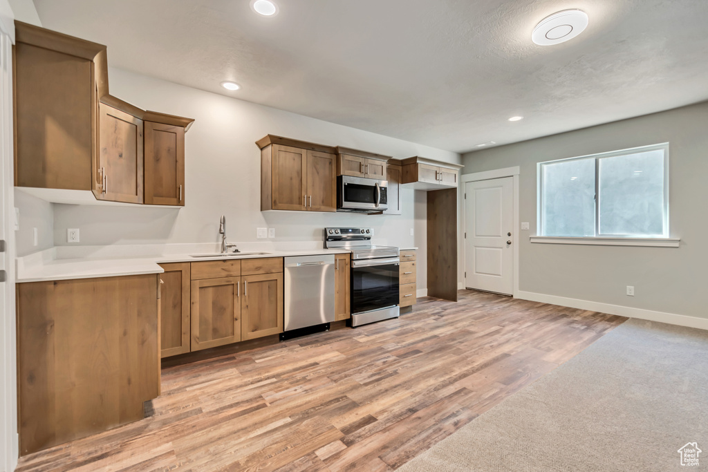 Kitchen with stainless steel appliances, sink, and light hardwood / wood-style flooring
