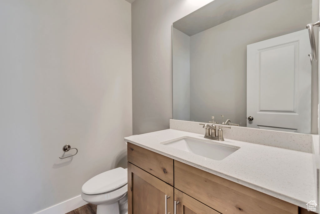Bathroom featuring hardwood / wood-style floors, toilet, and vanity