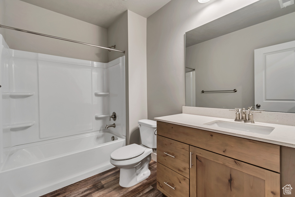 Full bathroom with tub / shower combination, hardwood / wood-style floors, toilet, and vanity with extensive cabinet space