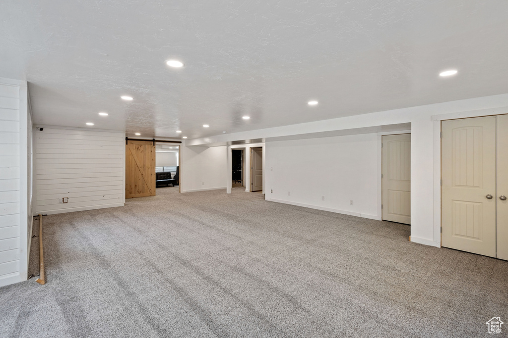 Unfurnished living room with light colored carpet and a barn door