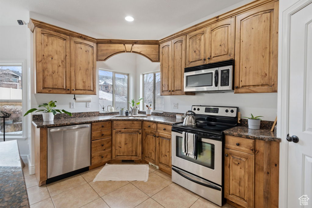 Kitchen with light tile flooring, appliances with stainless steel finishes, sink, and plenty of natural light