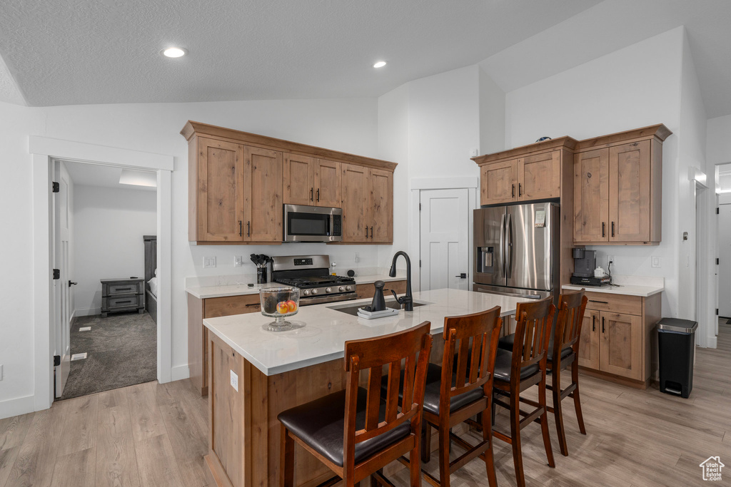 Kitchen featuring a kitchen island with sink, sink, a kitchen breakfast bar, light hardwood / wood-style flooring, and stainless steel appliances