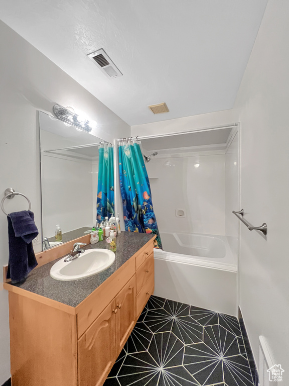 Bathroom featuring vanity with extensive cabinet space, shower / bath combination with curtain, and tile floors