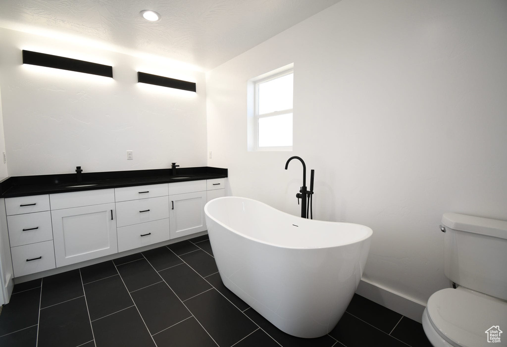Bathroom featuring vanity, toilet, a bathing tub, and tile floors