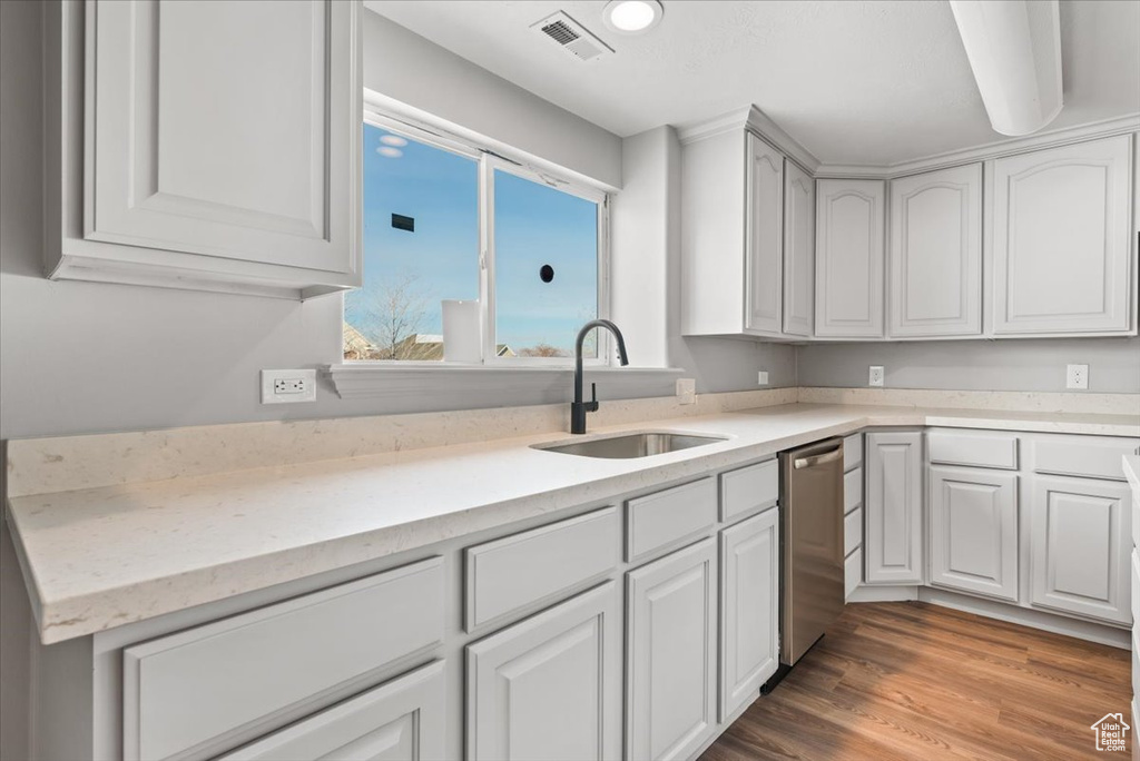 Kitchen featuring sink, white cabinetry, hardwood / wood-style flooring, and stainless steel dishwasher