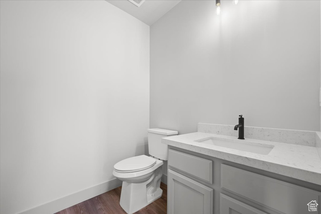 Bathroom featuring wood-type flooring, toilet, and vanity