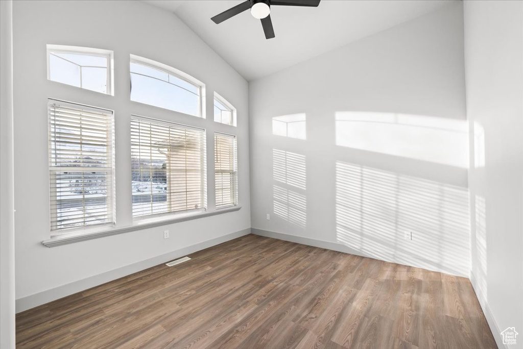 Unfurnished room featuring dark hardwood / wood-style flooring, ceiling fan, and a healthy amount of sunlight