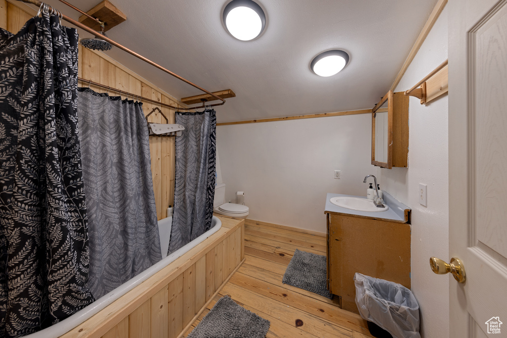 Full bathroom with shower / bath combination with curtain, toilet, vanity, and hardwood / wood-style floors