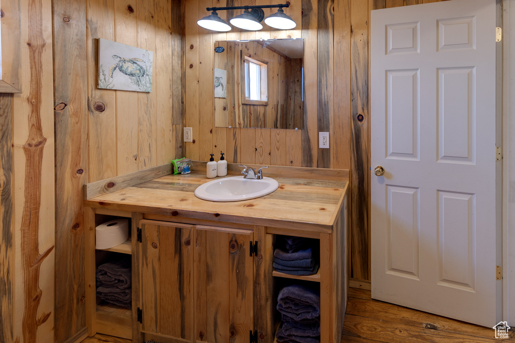 Bathroom with wood walls, hardwood / wood-style floors, and vanity