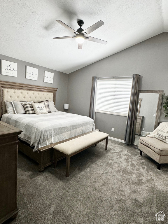 Bedroom with a textured ceiling, dark colored carpet, lofted ceiling, and ceiling fan