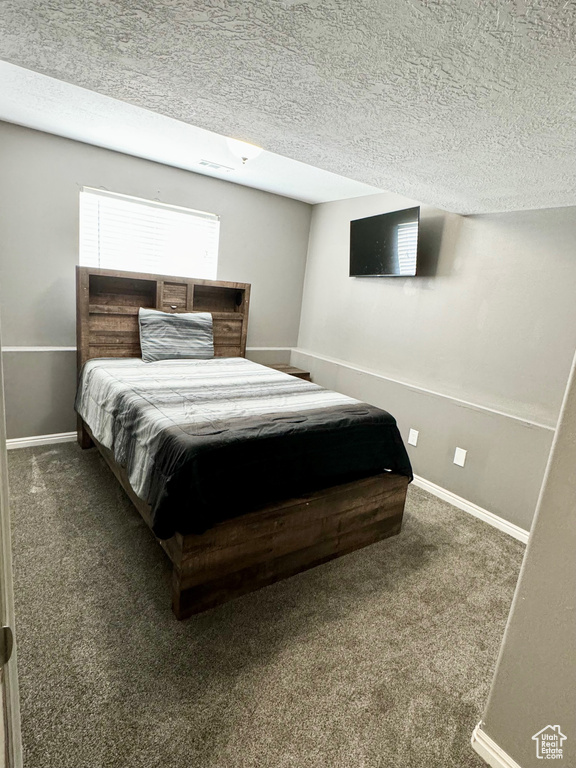 Bedroom featuring dark colored carpet and a textured ceiling
