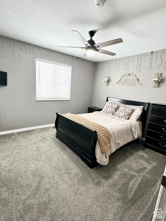 Bedroom with a textured ceiling, dark colored carpet, and ceiling fan