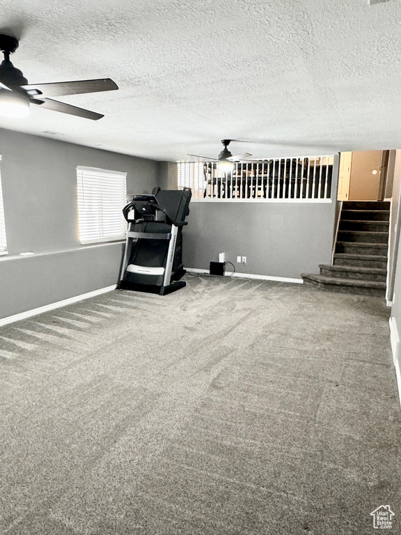 Interior space with a textured ceiling, carpet flooring, and ceiling fan
