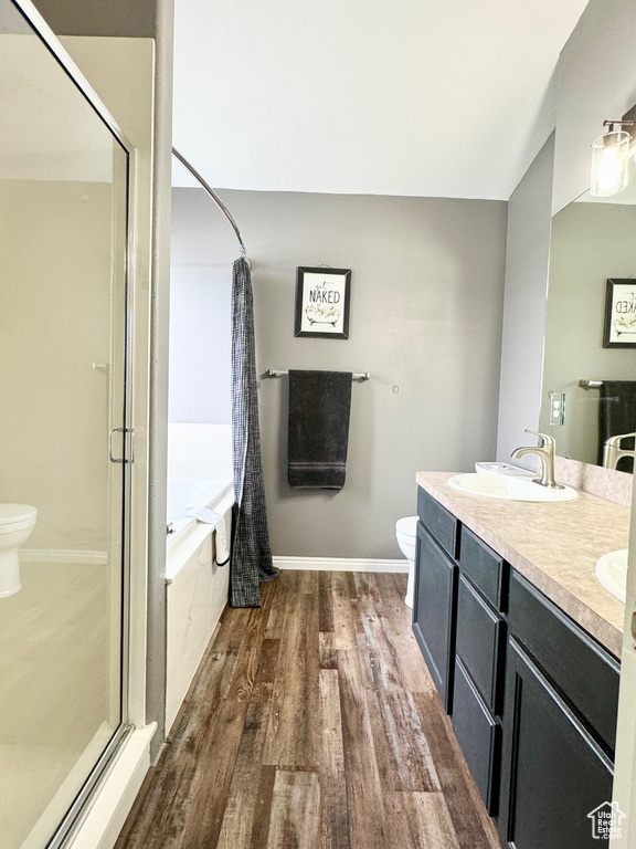 Full bathroom with toilet, separate shower and tub, double sink vanity, and hardwood / wood-style floors