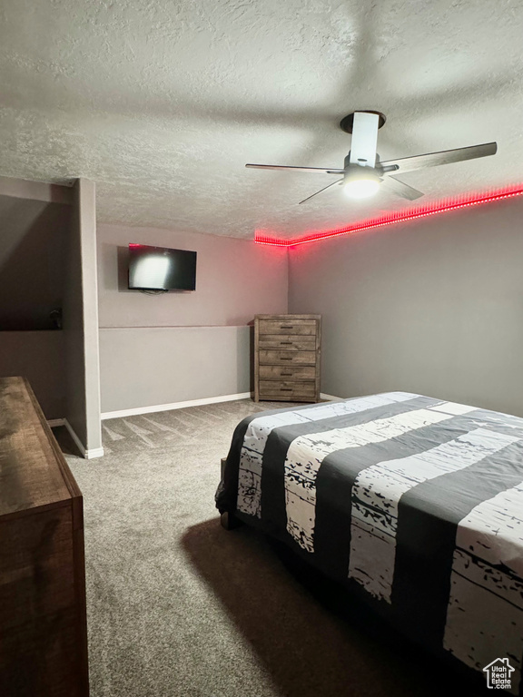 Bedroom with a textured ceiling, carpet flooring, and ceiling fan