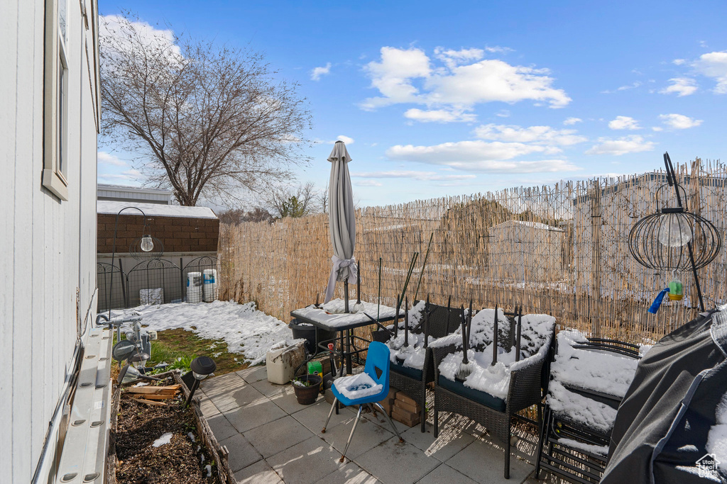 Snow covered patio with a storage shed