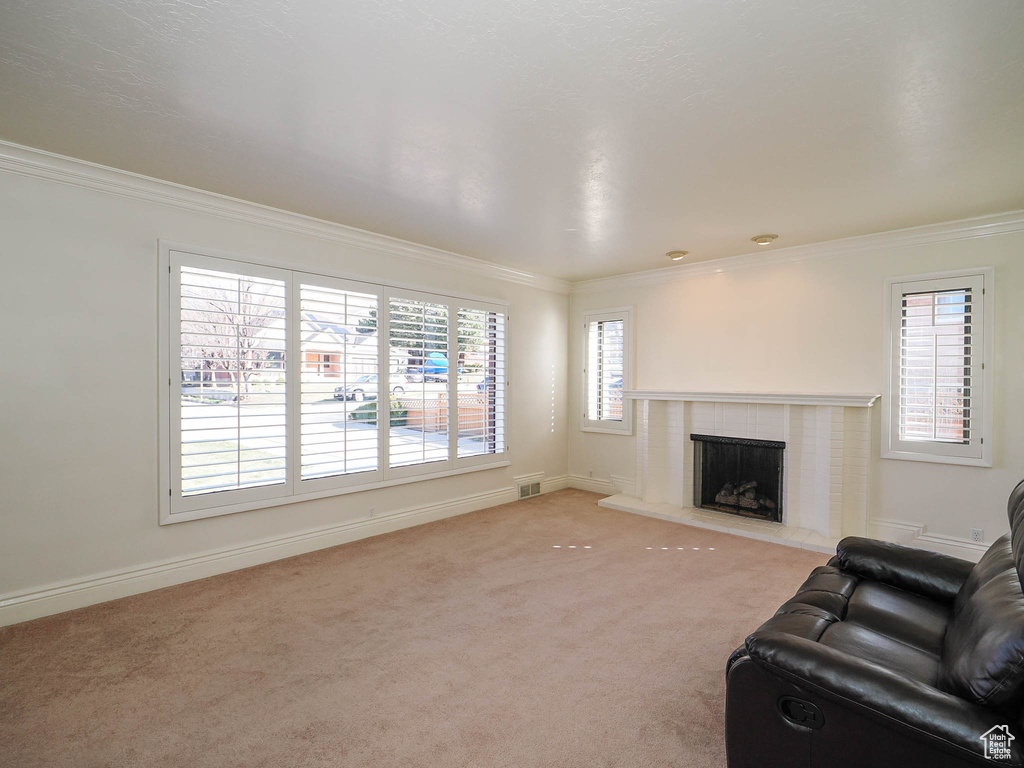 Living room featuring light colored carpet, crown molding, and a fireplace