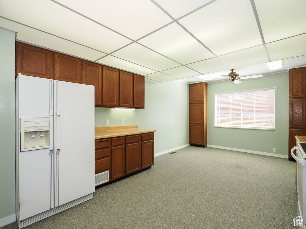Kitchen featuring light carpet, white refrigerator with ice dispenser, a paneled ceiling, and ceiling fan
