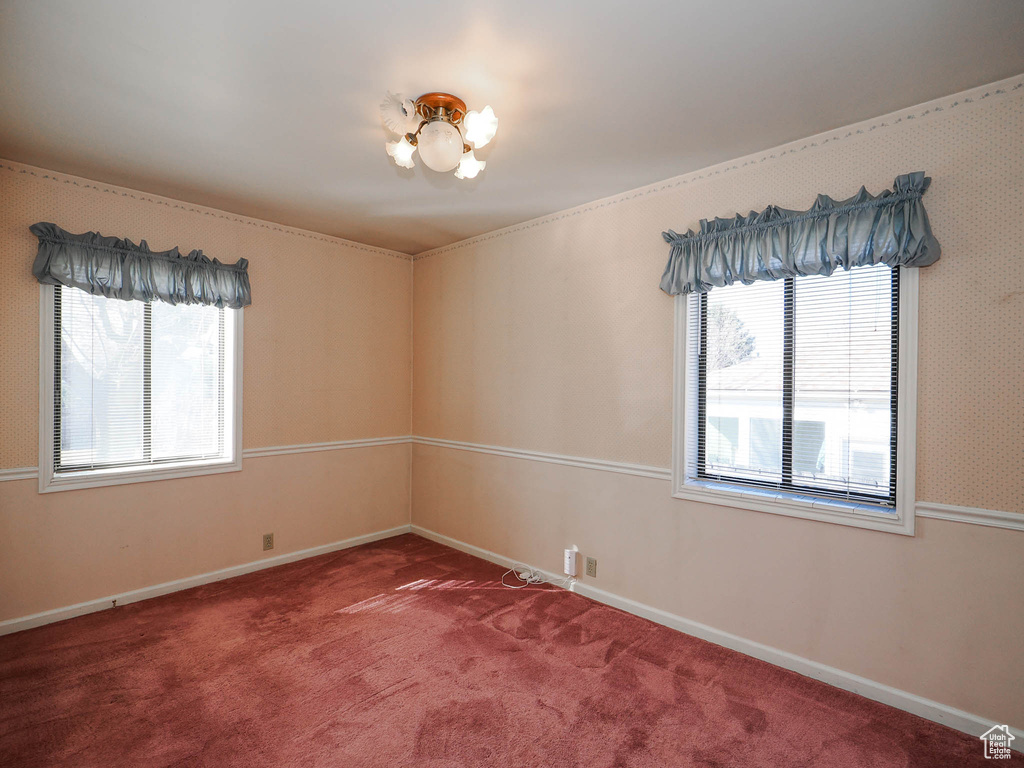 Carpeted spare room with a notable chandelier and a wealth of natural light